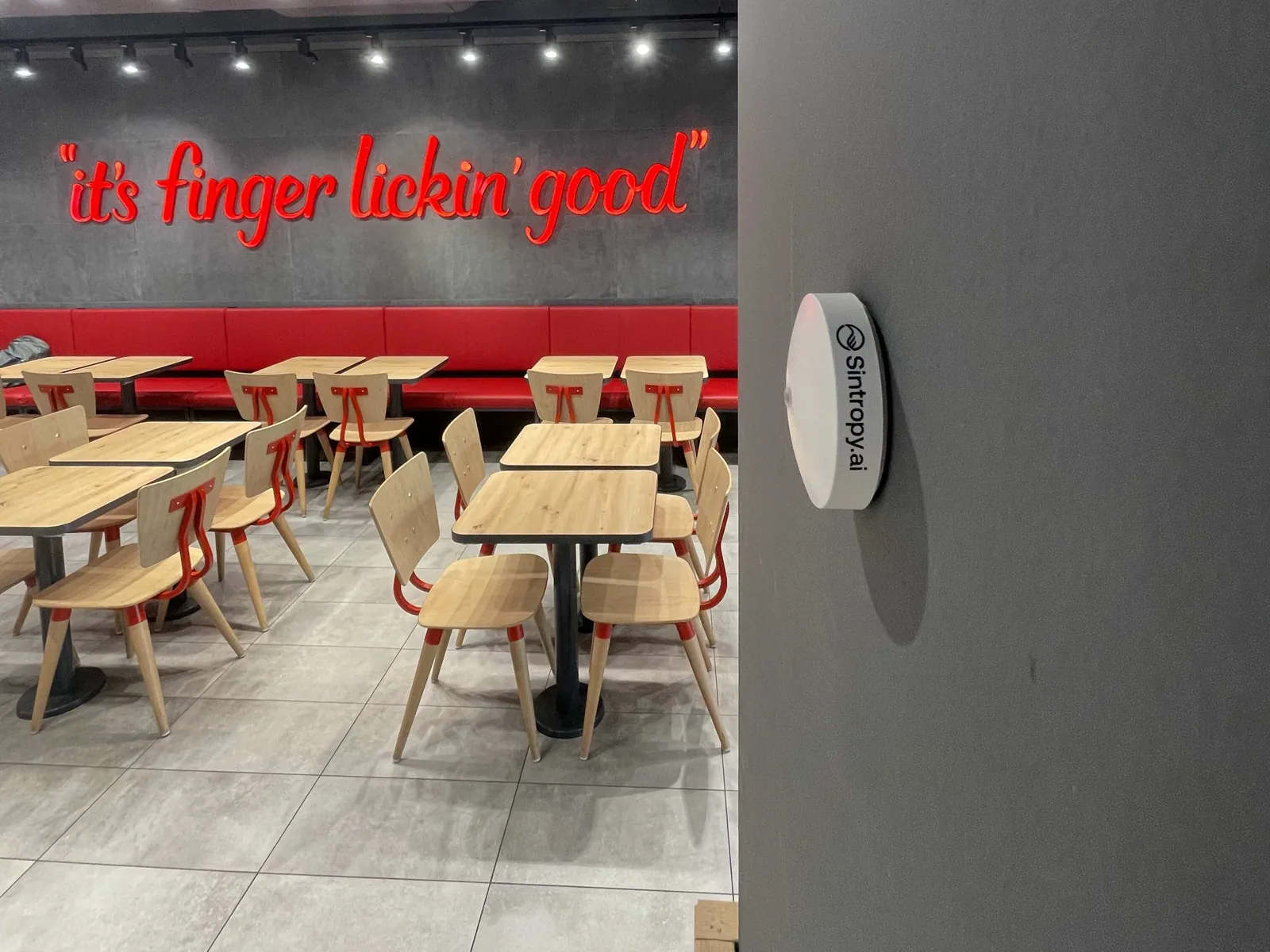 Sensore Sintropy a parete in un punto vendita KFC, con la sala e le postazioni sullo sfondo
